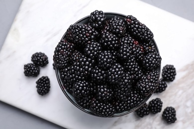 Photo of Fresh ripe blackberries in bowl on table, flat lay