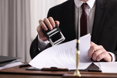 Notary stamping document at table in office, closeup