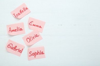 Choosing baby's name. Paper stickers with different names on white wooden background, flat lay. Space for text