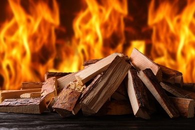 Image of Dry wood and burning fire on background. Cozy atmosphere