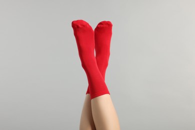 Woman in stylish red socks on light grey background, closeup