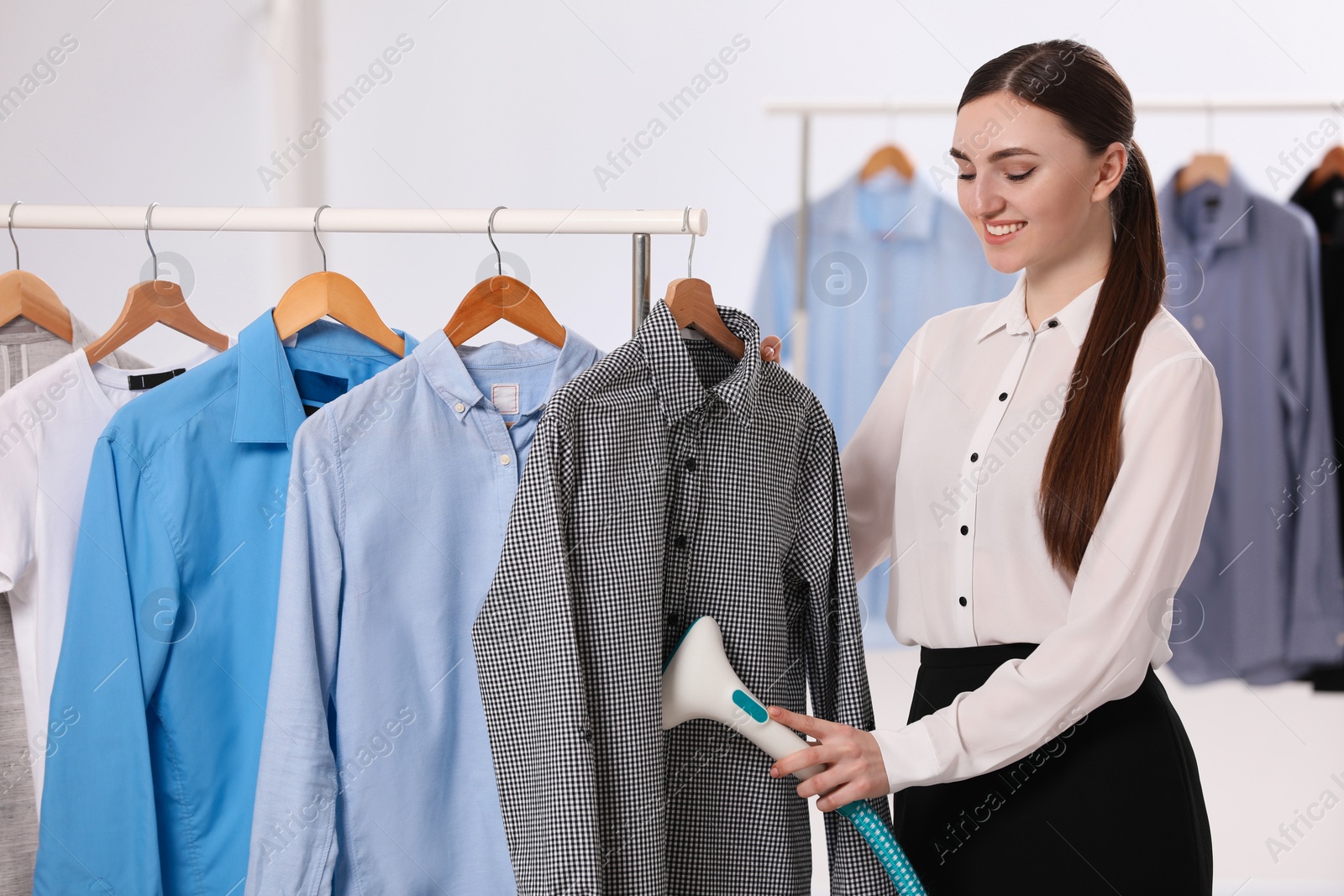 Photo of Woman steaming shirt on hanger in room