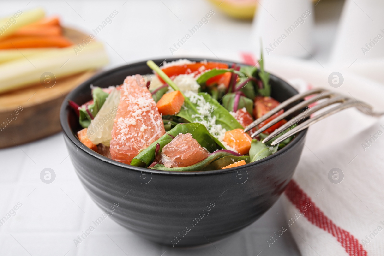 Photo of Delicious salad with pomelo, tomatoes and cheese on white tiled table, closeup