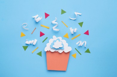 Photo of Paper cupcake and confetti on light blue background, flat lay