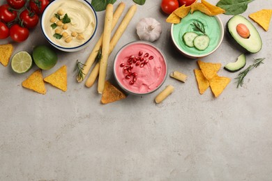 Photo of Different kinds of tasty hummus and snacks on light table, flat lay. Space for text