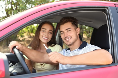 Happy young couple in new car on road trip