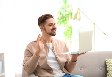 Photo of Man using laptop for video chat in living room