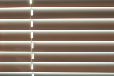 Photo of Closed modern white window blinds as background, closeup view