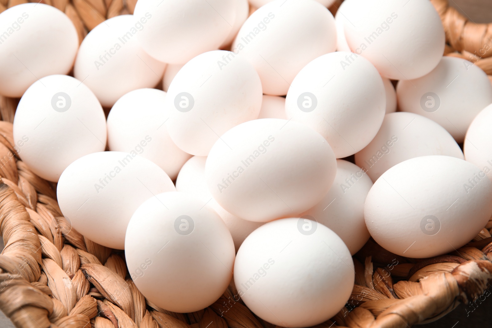 Photo of Pile of raw white chicken eggs in basket