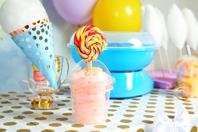 Photo of Plastic cup with cotton candy and candies on table at party