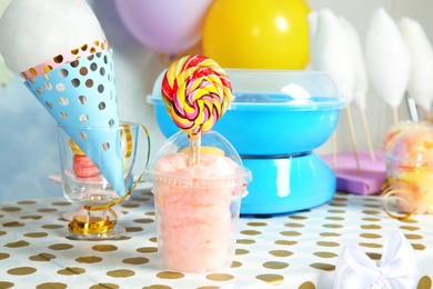 Plastic cup with cotton candy and candies on table at party