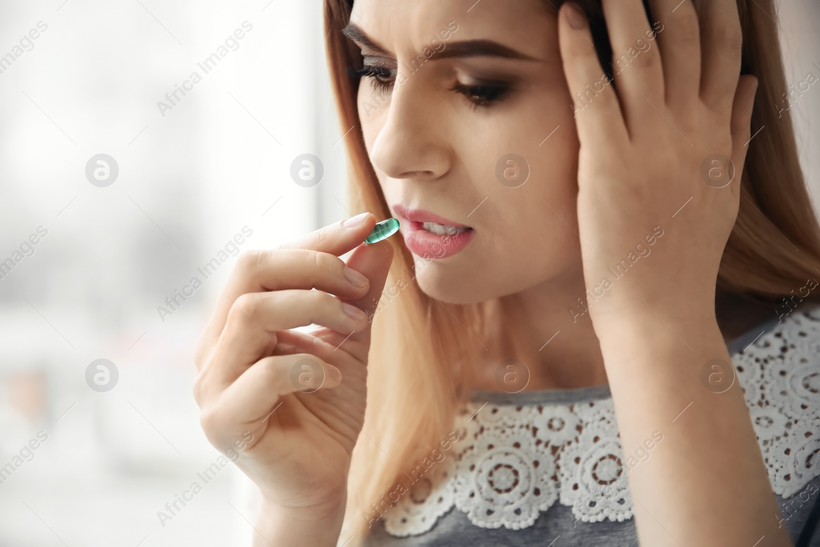 Photo of Young woman taking pill indoors