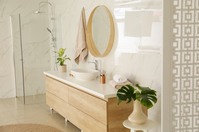 Round mirror over vessel sink in stylish bathroom interior