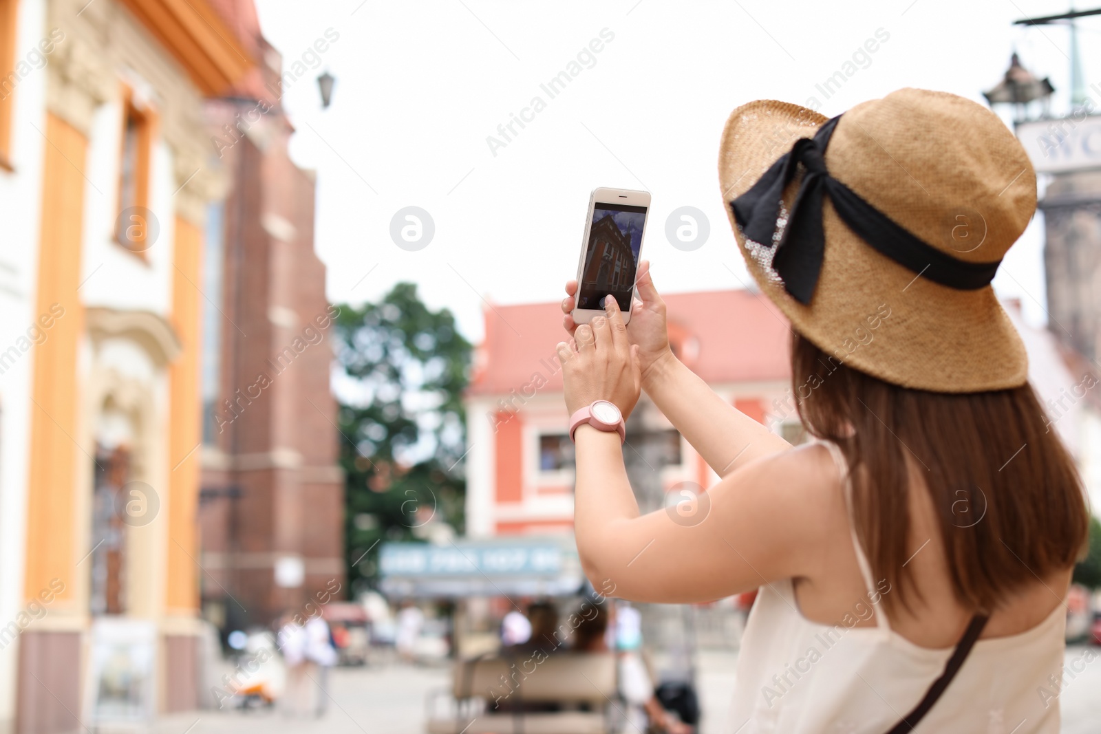 Photo of Young woman taking photo of building on city street