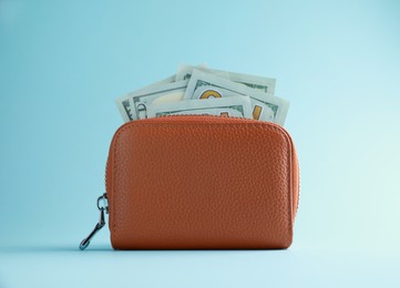 Photo of One open leather purse with money on light blue background