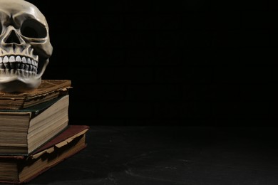 Photo of Human skull with books on black background, space for text
