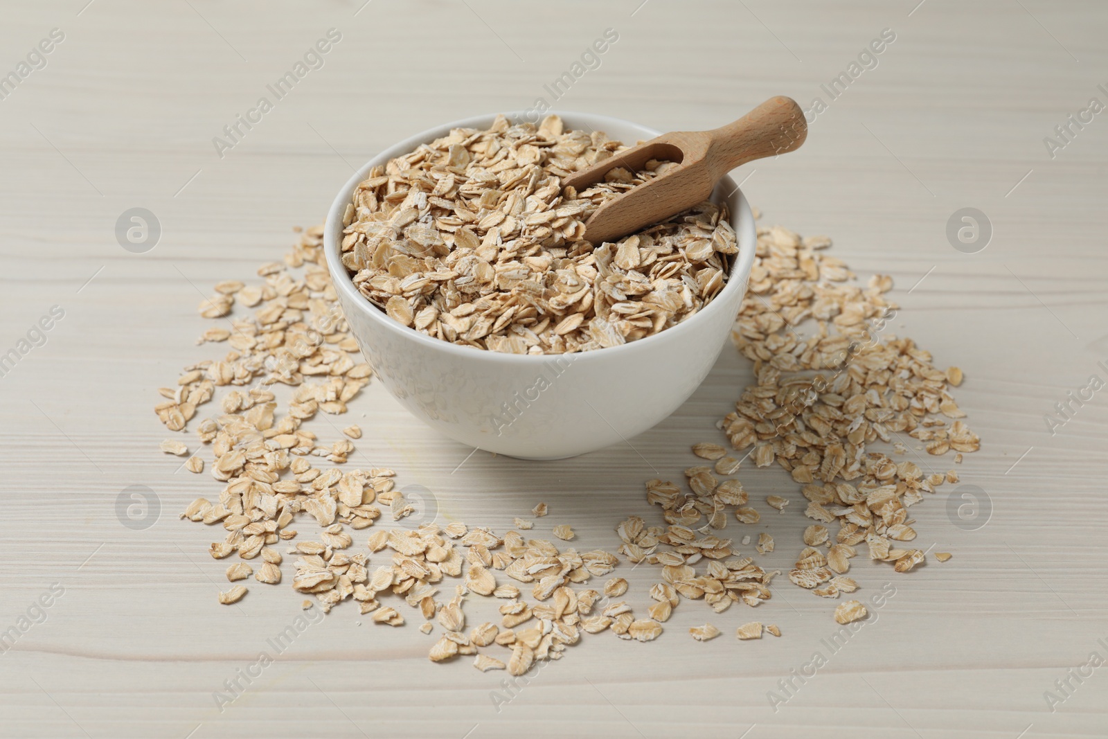 Photo of Bowl with oatmeal and scoop on white wooden table