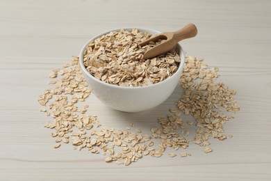 Bowl with oatmeal and scoop on white wooden table