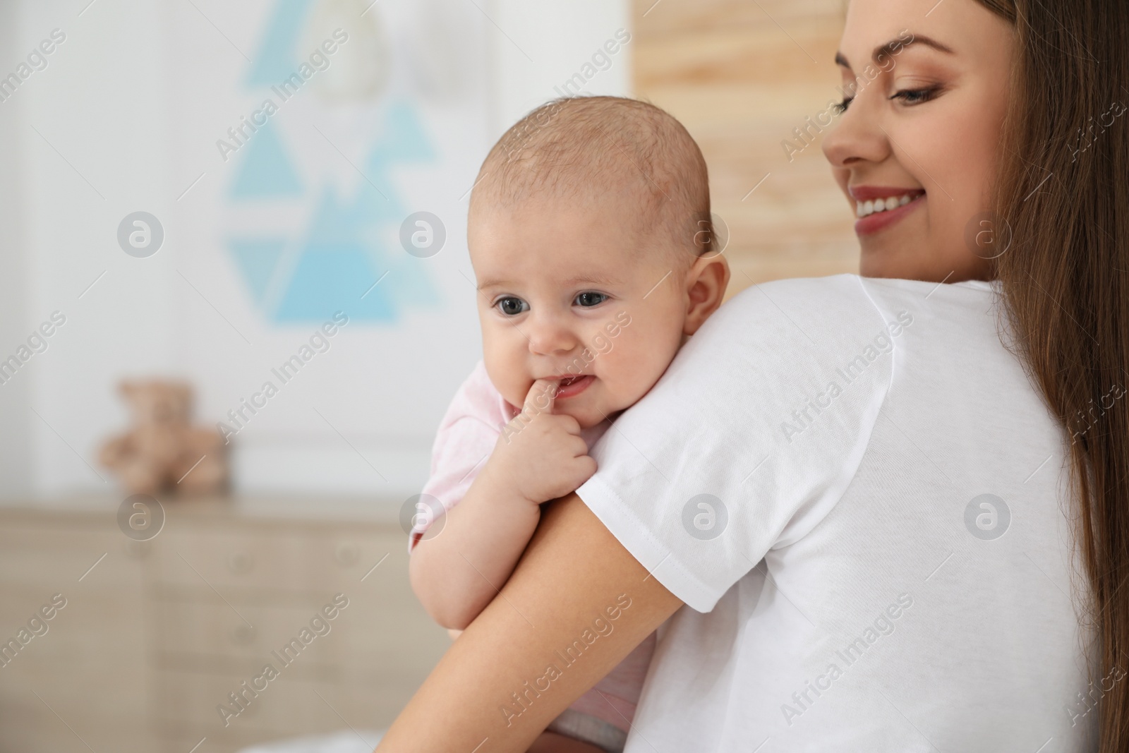 Photo of Mother holding her adorable baby at home. Space for text