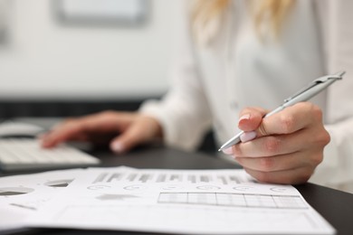 Photo of Secretary working with document at table in office, closeup