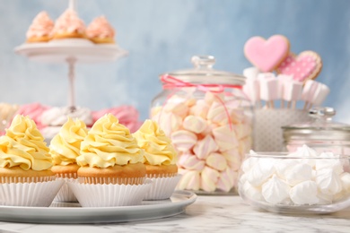 Photo of Candy bar with different sweets on white marble table. Space for text