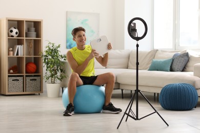 Smiling sports blogger holding floor scales while streaming online fitness lesson with phone at home