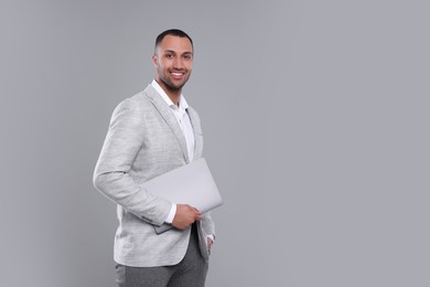 Photo of Young businessman in formal outfit with laptop on grey background. Space for text