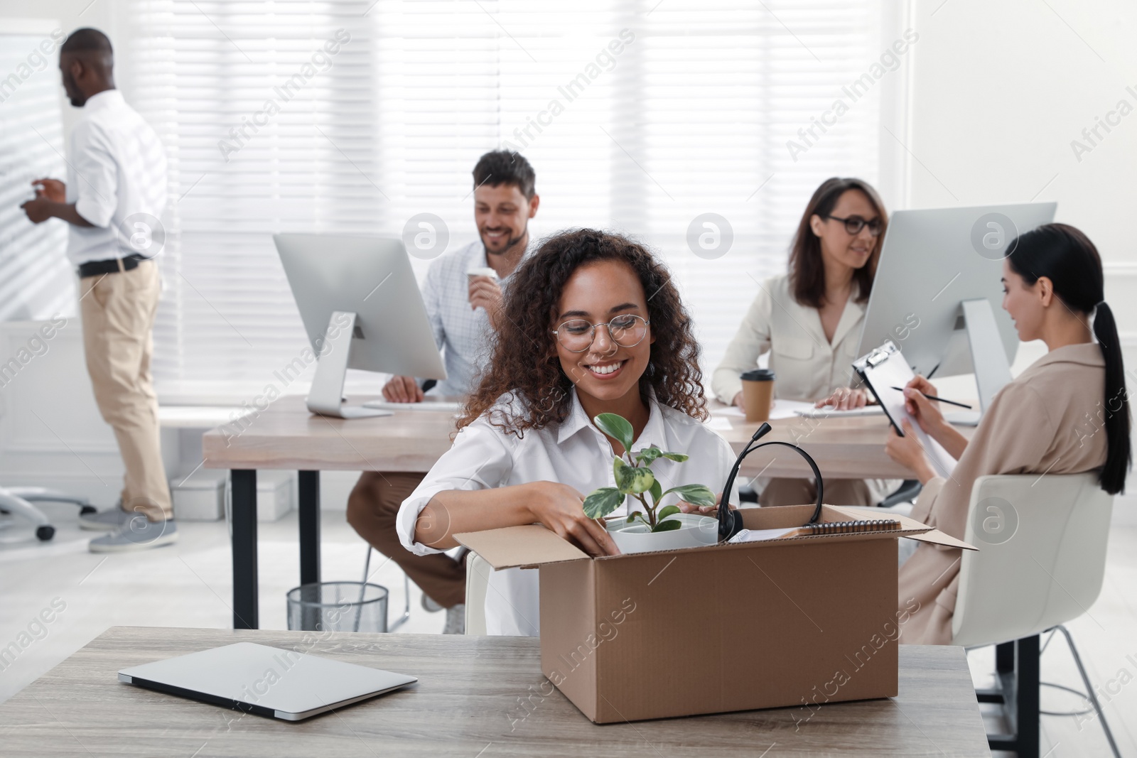 Photo of New coworker unpacking box with personal items at workplace in office