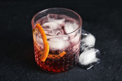 Photo of Glass of refreshing cocktail with ice cubes on dark background