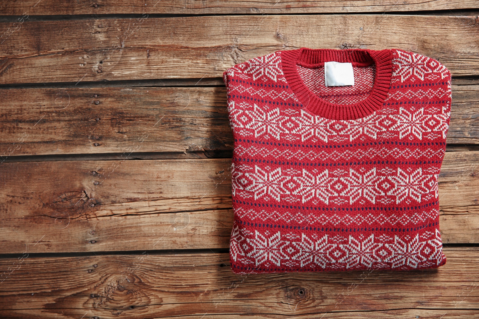 Photo of Christmas sweater with pattern and space for text on wooden background, top view