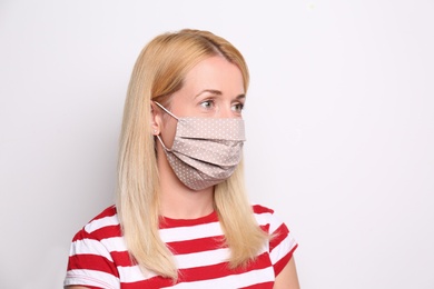 Photo of Woman wearing handmade cloth mask on white background. Personal protective equipment during COVID-19 pandemic