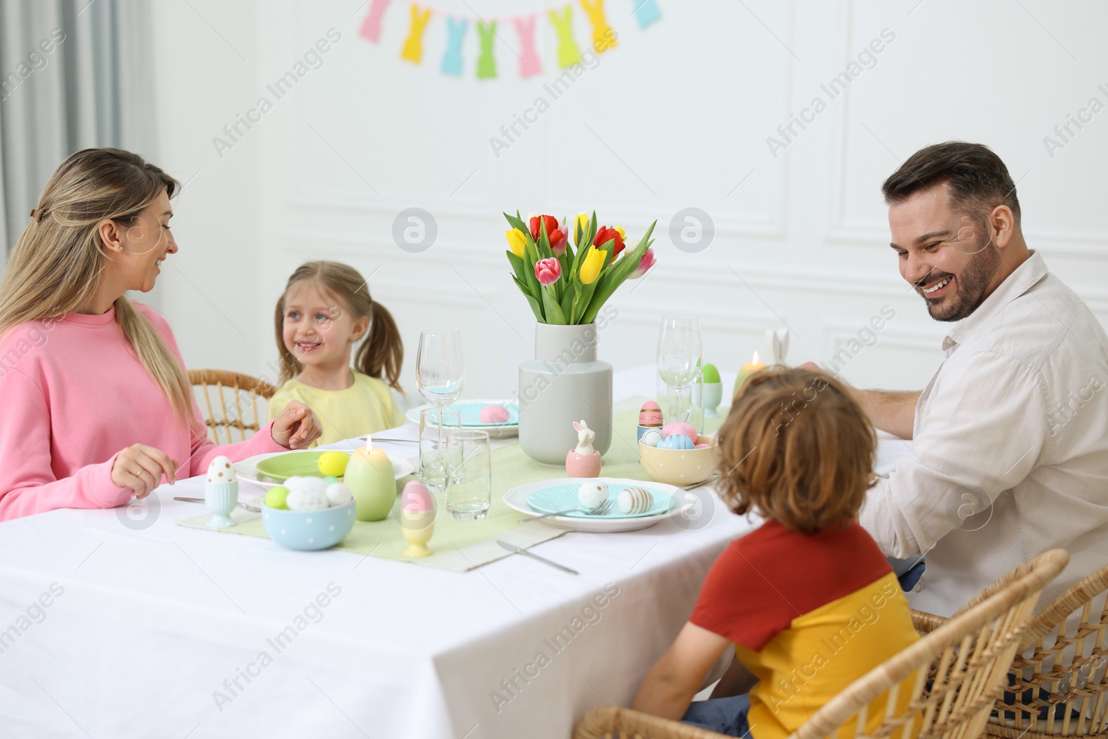 Photo of Cute family celebrating Easter at served table in room