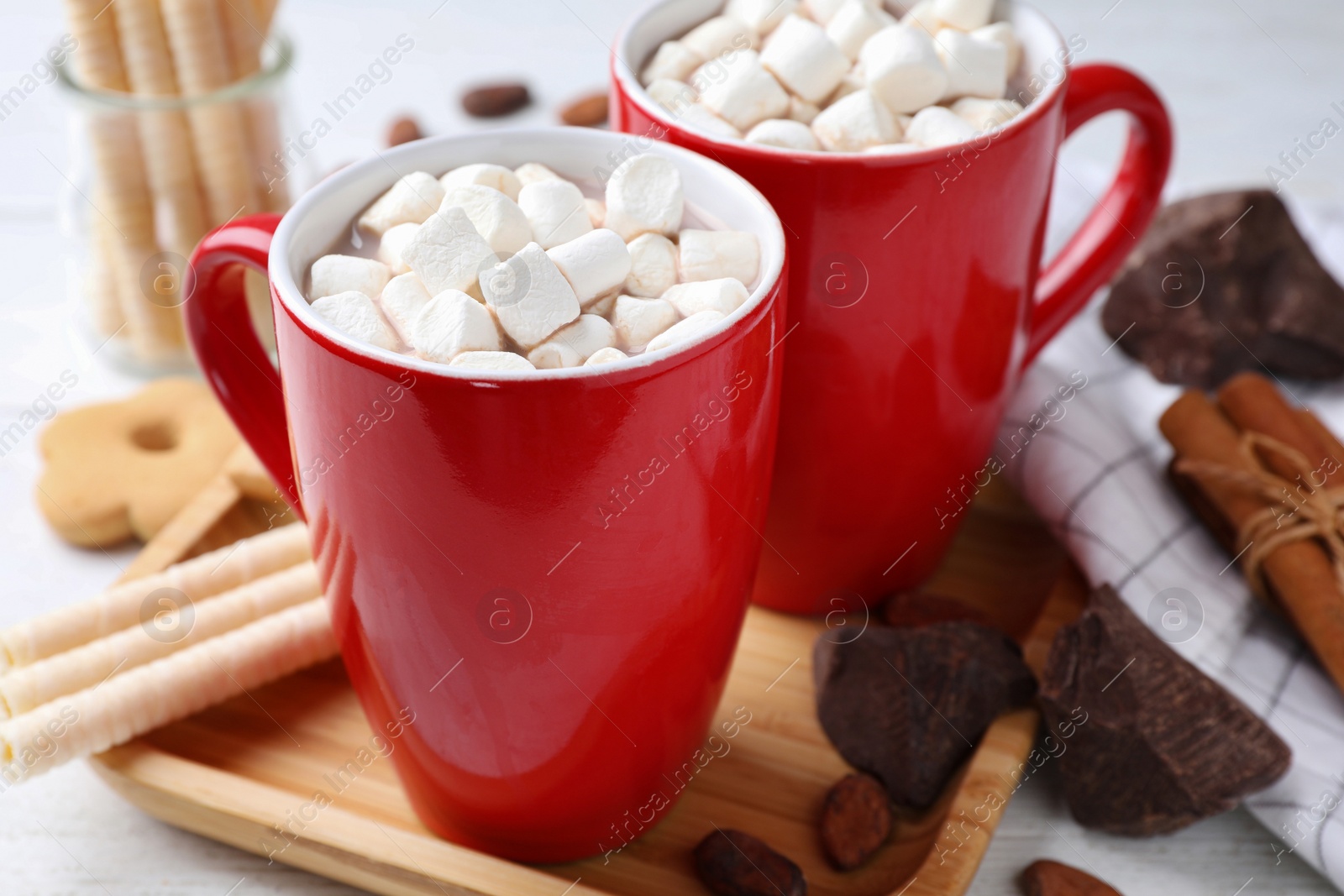 Photo of Composition of tasty cocoa with marshmallows in cups on white wooden table