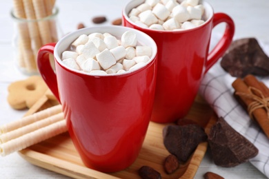 Photo of Composition of tasty cocoa with marshmallows in cups on white wooden table