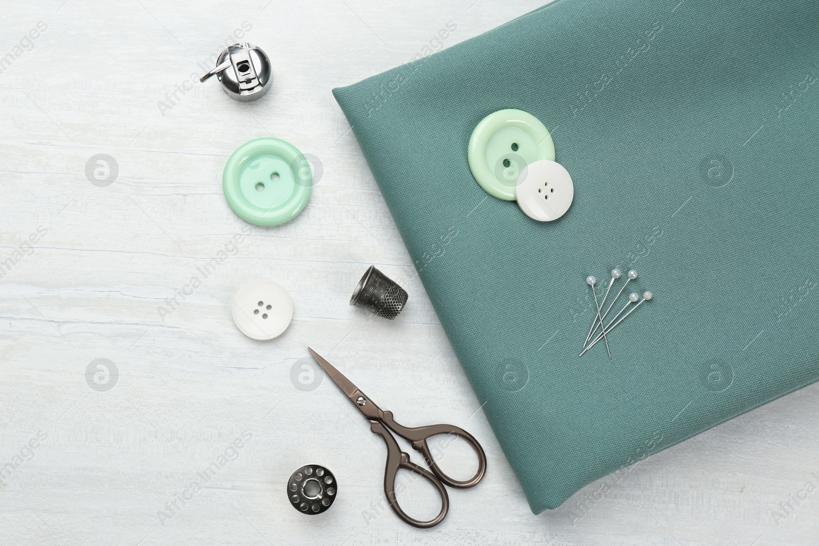 Photo of Flat lay composition with different sewing supplies and fabric on white wooden table