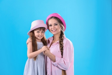 Photo of Happy woman and daughter in stylish clothes on color background