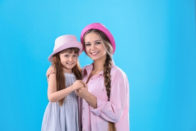 Happy woman and daughter in stylish clothes on color background