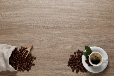 Photo of Cup of aromatic hot coffee and beans on wooden table, flat lay. Space for text