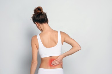 Image of Woman suffering from pain in back on light grey background