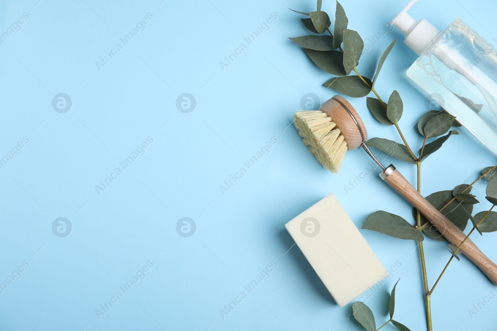 Photo of Flat lay composition with cleaning product and tools on light blue background, space for text. Dish washing supplies