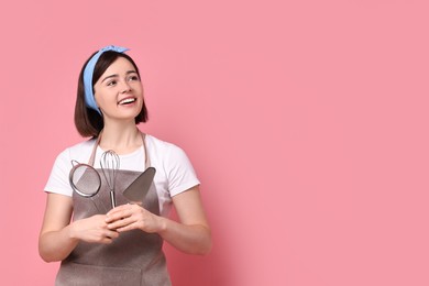 Photo of Happy confectioner with professional tools on pink background, space for text