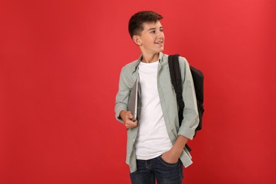 Photo of Teenage student with backpack and laptop on red background