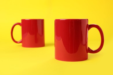 Two red ceramic mugs on yellow background