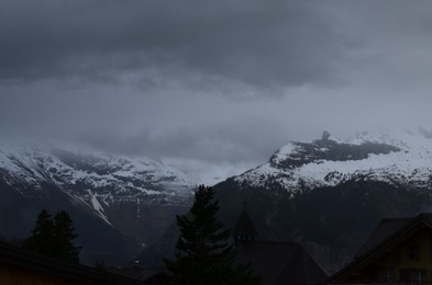 Picturesque view of cottage village and mountains covered with fog