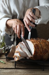 Photo of Woman cutting delicious baked ham at wooden table, closeup