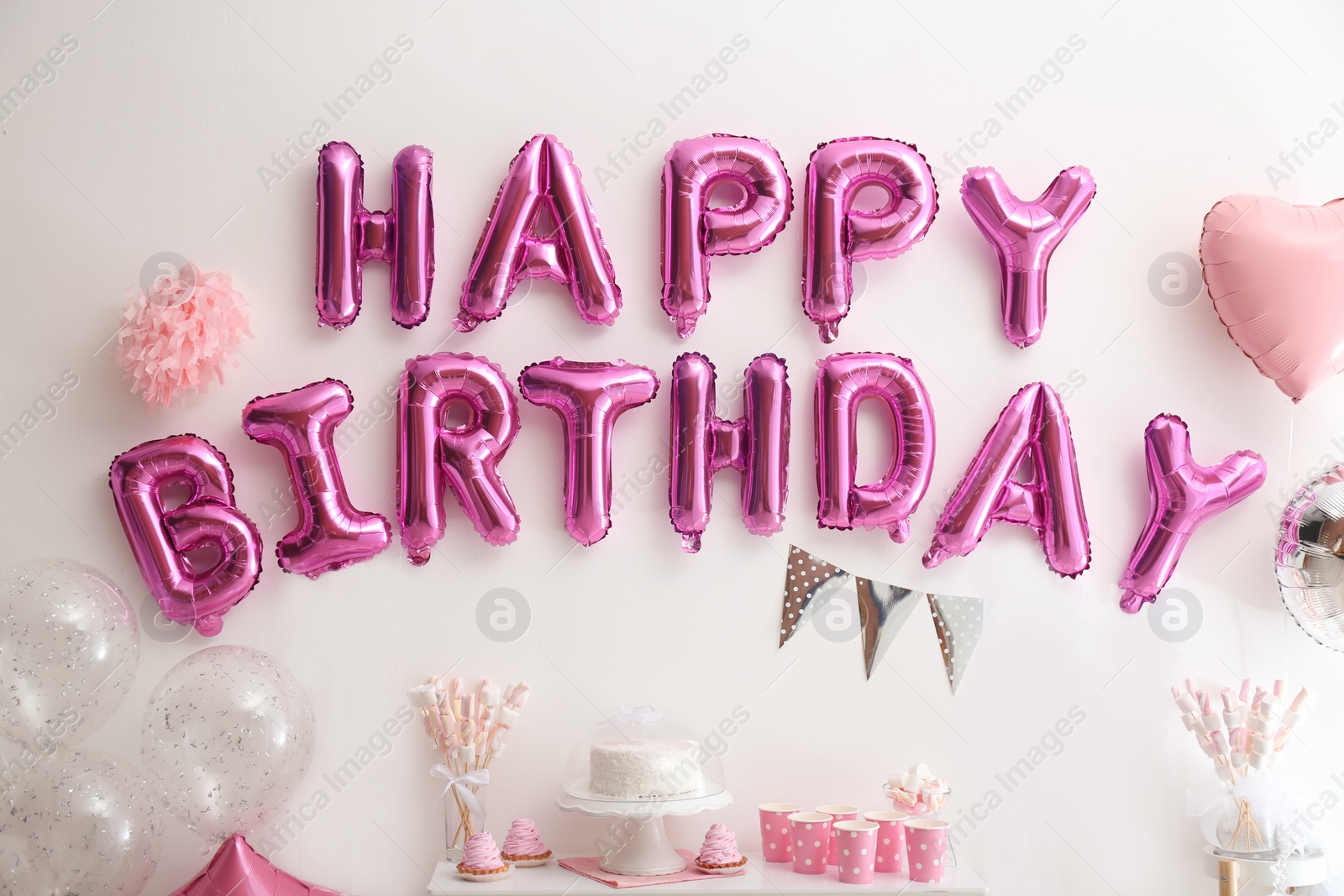 Photo of Phrase HAPPY BIRTHDAY made of pink balloon letters on white wall