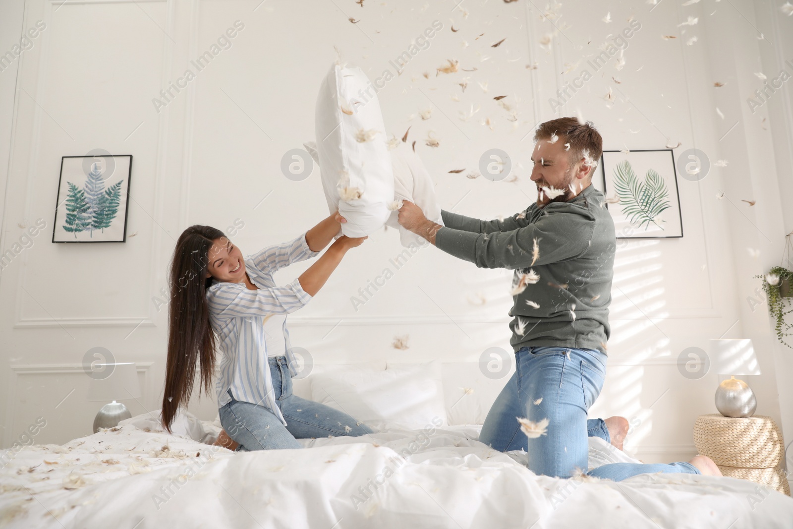 Photo of Happy young couple having fun pillow fight in bedroom