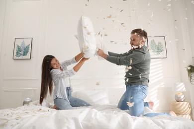 Happy young couple having fun pillow fight in bedroom