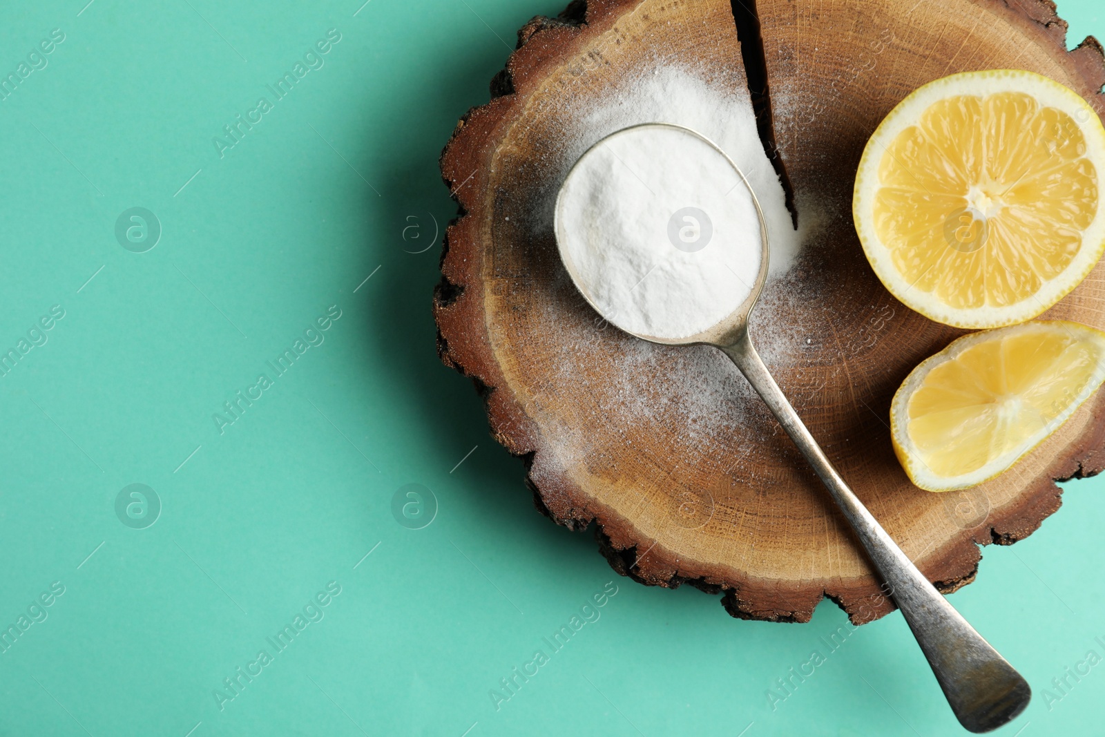 Photo of Baking soda and lemons on turquoise background, top view. Space for text