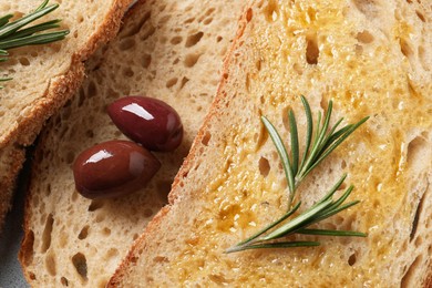 Photo of Tasty bruschettas with oil, rosemary and olives, top view